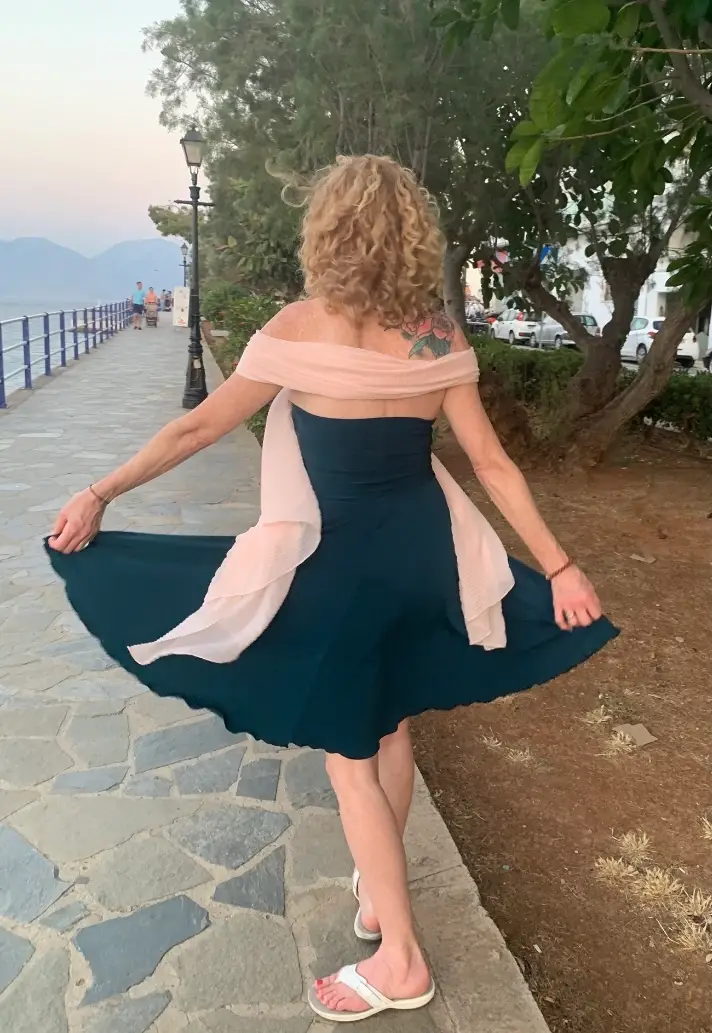 Ginger mid-turn on a seafront promenade at dusk, the skirt of her dress caught in the movement