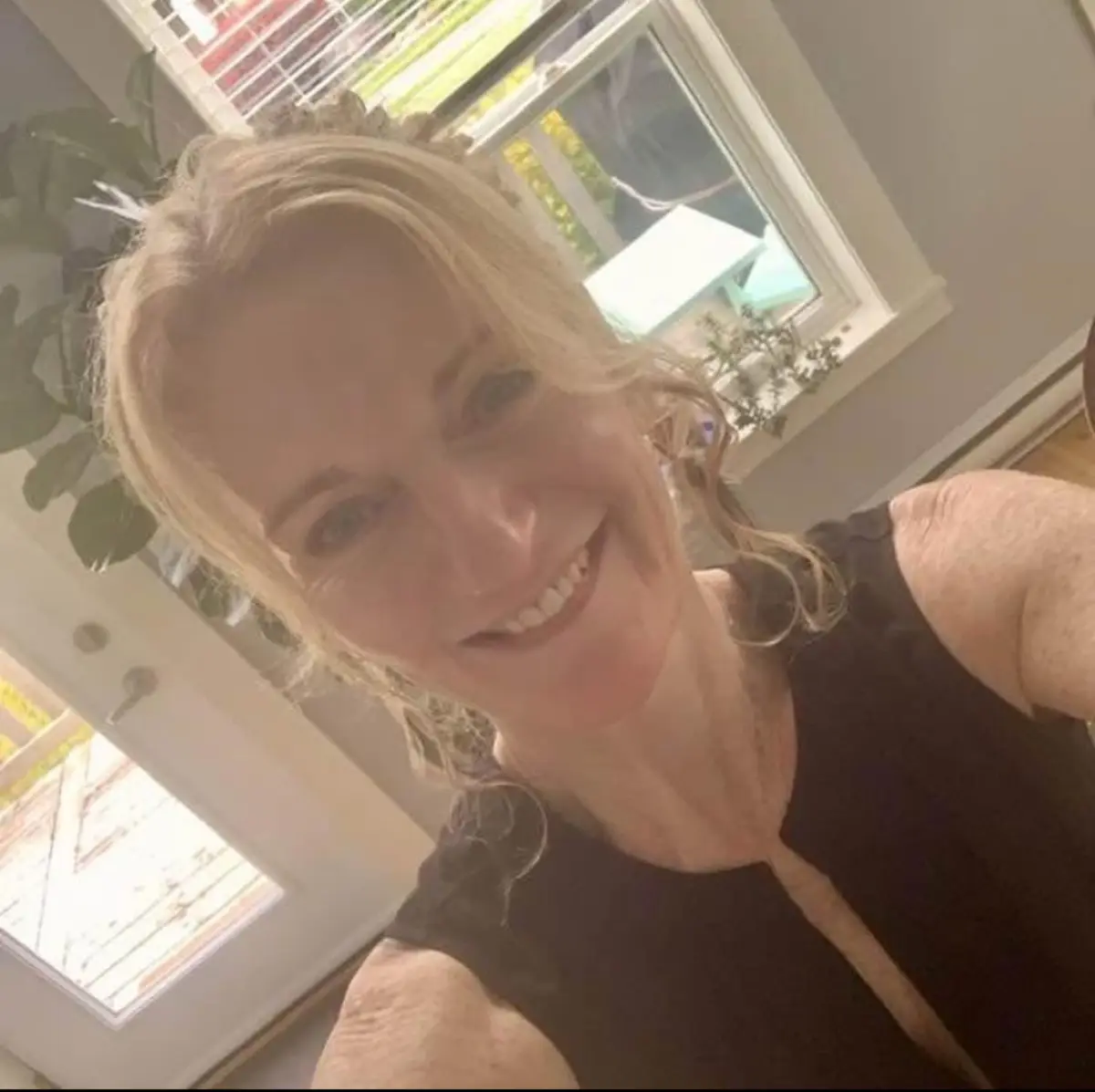 Ginger Canning smiling, in daylight by a window